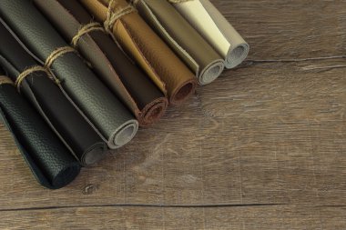 Leather pieces rolled with cord on the wooden table clipart
