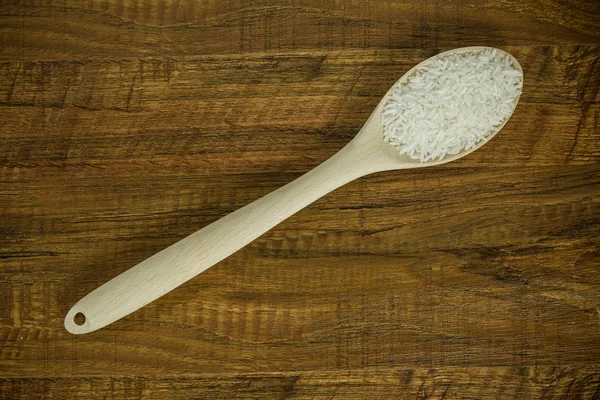 Wooden spoon diagonal of the table with rice — Stock Photo, Image