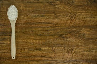 Pirinç ve tahta kaşık tablonun sol tarafında