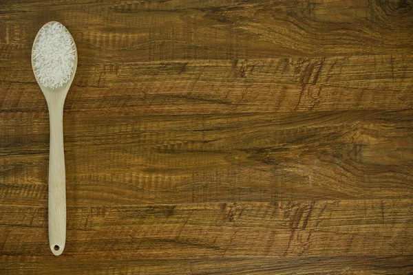 Pirinç ve tahta kaşık tablonun sol tarafında