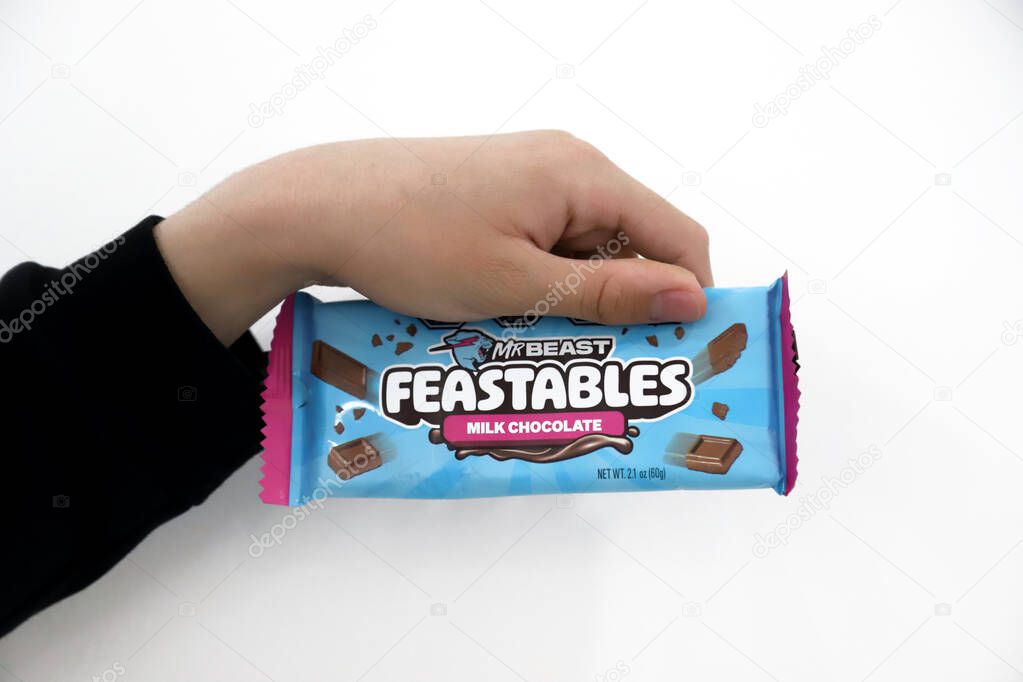 Kid holding a Mr. Beast Feastables Milk Chocolate bar. Isolated white background with copyspace