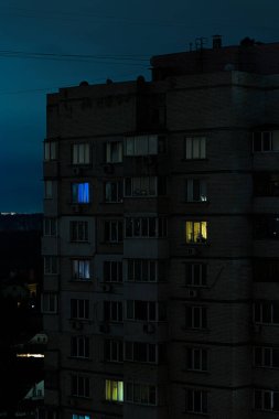 Geceleri Ukrayna 'da karanlık bir apartman binası ve elektrik kesintisi sırasında çok az sayıda parlayan pencere.