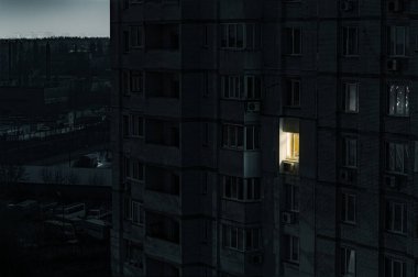 Ukrayna 'daki bilinç kaybı sırasında karanlık bir apartmanın ön cephesinde tek ışıklı pencere.