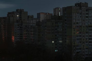 Çok katlı Sovyet döneminden kalma çok katlı apartman bloklarının dış çekimleri, elektrik kesintileri sırasında çok az sayıda dağınık pencerenin yandığını gösteriyor..