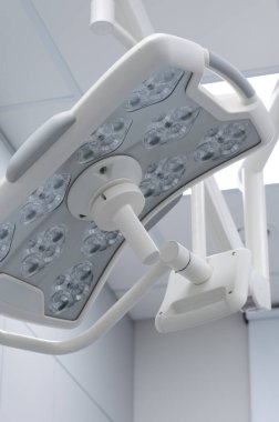 Steril hastane ameliyathane ortamında birden fazla ampul asılı modern beyaz LED cerrahi aydınlatma armatürünün düşük açılı görüntüsü