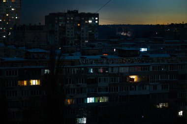 Rusya 'nın enerji şebekesine yaptığı saldırıların yol açtığı toplam elektrik kesintisi sırasında Kyiv' de sadece birkaç ışıklı penceresi olan çok katlı bir apartman manzarası - 24 Ocak 2026