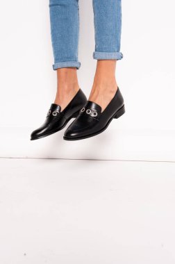 Siyah deri okul ayakkabıları ve beyaz arka planda kot pantolon.