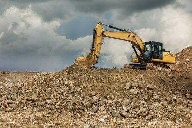 Bir taş ocağında kazıcı, taşa dönüşmesi için taşı çıkarıyor.