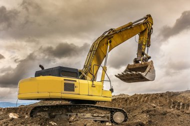 Kazıcı, İspanya 'da bir yamaç inşaatı için bir kamyonu toprakla dolduruyor.