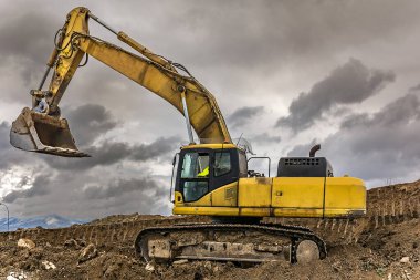 Kazıcı, İspanya 'da bir yamaç inşaatı için bir kamyonu toprakla dolduruyor.