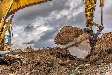 Bir yol inşa etmek için toprak yüklü bir kazıcının küreğinin ayrıntıları