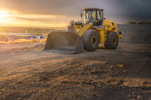Excavator on the construction site of a road in a sunset