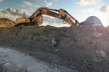Kazıcı inşaat alanında toprak ve kum taşıyor.