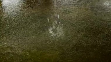Su birikintisinde büyük yağmur damlaları. Ağır çekimde su sıçraması. Şiddetli yağmur inanılmaz damlalar ve bol miktarda su yaratır. Terli bir binada terlemek..