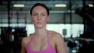 İyi aydınlatılmış bir spor salonundaki modern bir koşu bandında yoğun bir şekilde koşan pembe atletik giysili fit bir kadın. Odaklanmış kardiyo seansı: tanımlanmış sırt kasları olan atletik bir kadın kapalı alanda koşuyor. Parlak spor salonunun pencerelerinin altında adım adım ezici hedefler