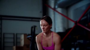 Kadının güzel bir atletik vücudu var ve dambılları güçlü bir şekilde kaldırıyor. Pembe bluzlu kadın antrenör ve şortlu spor salonunda dambıllarla çömelme hareketi yapıyor. Kadın sporcuların aktif fitness egzersizleri.