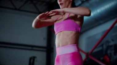 Güzel karın kasları olan bir kadın spor salonunda ısınıyor. Sporcu kadının aktif fitness eğitimi. Spor öncesi esneme egzersizleri yapan rahatlamış vücutlu antrenör..