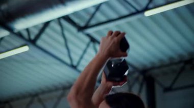 Spor salonunda halterle egzersiz yapan bir kadın. Pembe bluzlu ve şortlu spor kadınlarının aktif fitness eğitimi. Vücut geliştirme egzersizi yapan antrenör..