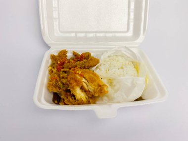 Nasi ayam geprek ya da beyaz arka planda izole edilmiş ambalaj kutusunda ezilmiş tavuk pirinci..