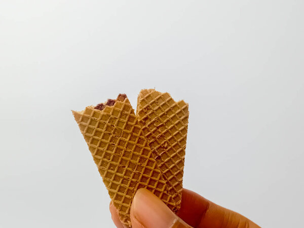 Рука держит шоколадную вафлю изолированы на белом фоне.
