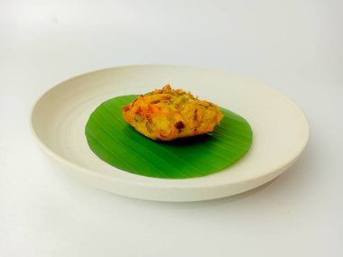 Ote-ote or Bala-bala or Bakwan is Vegetable Fritter, served on banana leaf and round plate, isolated on white background.