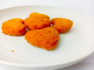 Tavuklu nugget beyaz arka planda izole edilmiş yuvarlak bir tabakta servis edilir. Fast food.
