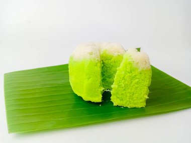 Putu Ayu, geleneksel Endonezya buğulama keki pandan yapılmış ve hindistan cevizi rendelenmiş. Bir parça kes ve muz yaprağında servis yap, beyaz arka planda izole edilmiş..