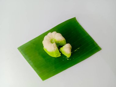 Putu Ayu, geleneksel Endonezya buğulama keki pandan yapılmış ve hindistan cevizi rendelenmiş. Bir parça kes ve muz yaprağında servis yap, beyaz arka planda izole edilmiş..