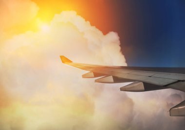 Uçak kanatları bulutların ve güneş ışığının arka planında uçuyor..