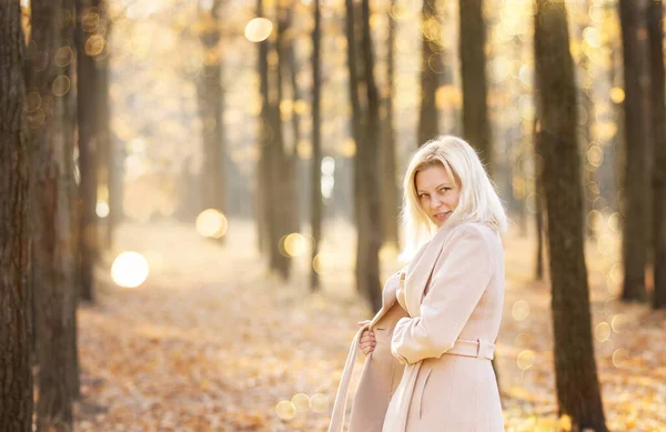 Happy middle-aged woman walking in the autumn park.