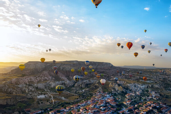Early morning in the valley with rocks and balloons in the sky at dawn. View from a height of the city and houses. Cappadocia. Turkey. Goreme.