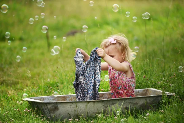 Mała Dziewczynka Sukience Siedzi Korycie Myje Rzeczy Zielonej Łące — Zdjęcie stockowe