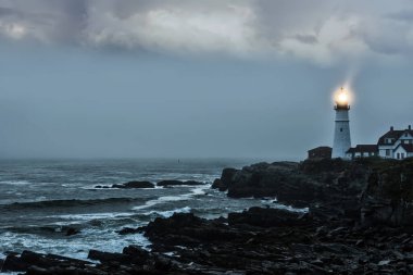 Kayalık bir sahildeki parlak bir deniz fenerinin kasvetli fotoğrafı. Ünlü deniz feneri. Portland demek. ABD. Maine