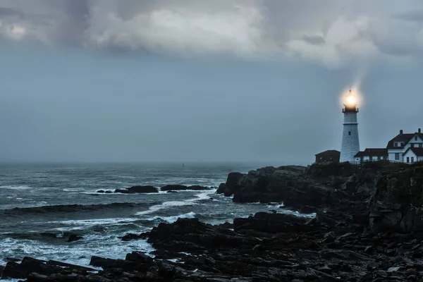 Kayalık bir sahildeki parlak bir deniz fenerinin kasvetli fotoğrafı. Ünlü deniz feneri. Portland demek. ABD. Maine
