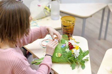 Buket süsleme dersi. Bir buket buketi kesen çocuk elleri. Anneler Günü 'nde ya da 8 Mart' ta anneme hediye hazırlıyorum..