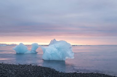 Güneş doğarken okyanus kıyısında yüzen buzlar. Buzul gölü. İzlanda. Bulanık suyla uzun süre maruz kalma.