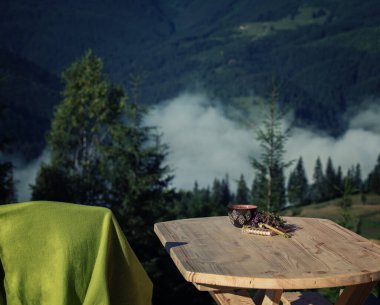Bir fincan bitki çayı, bir defter, bir kalem ve otlar yakınlardaki ahşap bir masada, dağ manzaralı bir çay için..