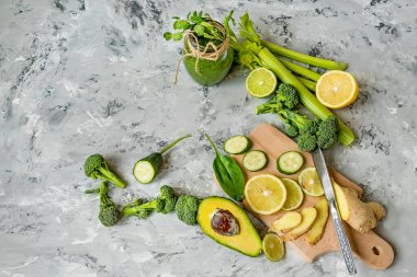Brokoli, salatalık, limon, zencefil sağlıklı bir meyve suyu için yeşil sebze. Gri beton arka planda farklı sebzeler ve yeşil bir meyve püresi. Yukarıdan görüntüle.