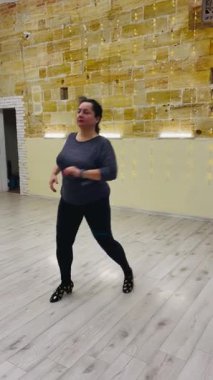 Kendinden emin, iri yarı bir kadın, büyük aynalar önünde antrenman yaparken vücut pozitifliğini ve özgürlüğünü kucaklayarak stüdyoda anlamlı dans hareketleri yapar.. 