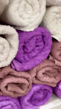 Rafta düzgünce sarılmış renkli havluların yakın çekimi. Hijyen, konfor, spa atmosferi ve ev düzenini temsil eden temiz ve düzenli depolama kavramı.