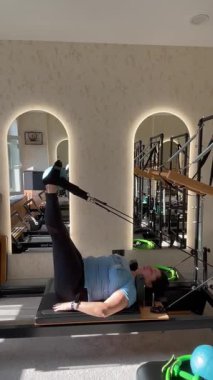 Artı modern bir fitness stüdyosunda pilates yapan boyunda bir kadın. Vücut sağlığı konsepti, güç, esneklik ve kapalı alanda egzersiz yaparken bilinçli hareket. yaşam tarzı fitness videosu.