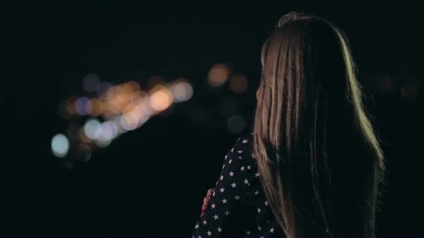 Вид сзади красивой женщины, смотрящей на ночной город — стоковое видео