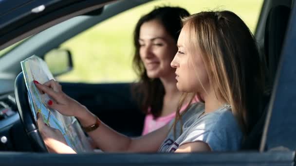 Deux jolies filles en voiture pavage itinéraire de voyage sur la carte — Video