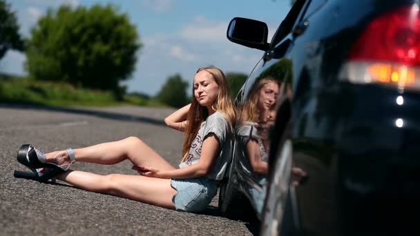 Chica rubia sentada en la carretera cerca de su coche roto — Vídeo de stock