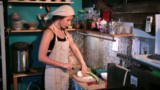 Jovem mulher cortando cebola na tábua de corte de madeira — Vídeo de Stock