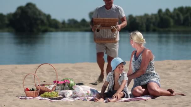 Счастливая семья, устраивающая пикник на пляже — стоковое видео