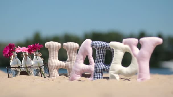 Parola felice tessuto imbottito lettere sulla sabbia — Video Stock