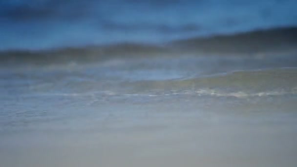 Волны медленно ломаются на берегу в ясный день — стоковое видео