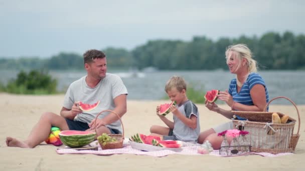 šťastná rodina jíst meloun na pláži