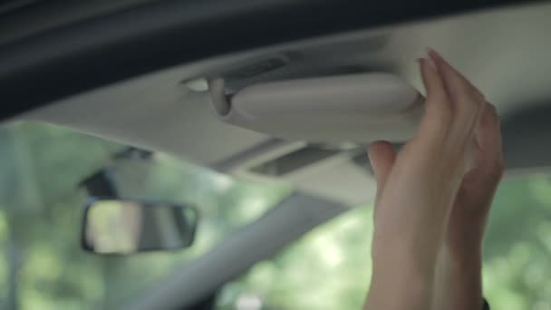 Closeup vrouwelijke hand nemen auto sleutel van zonneklep — Stockvideo